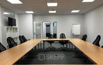 Moderner Konferenzraum in Berlin Friedrichshain mit großen Holztischen und schwarzen Stühlen, perfekt zum Bürofläche mieten in der Rigaer Straße 71a.