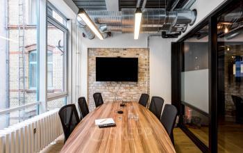 Conference room at Skalitzer Straße 104, Berlin Kreuzberg, featuring large windows, modern lighting, and a spacious wooden table with chairs.