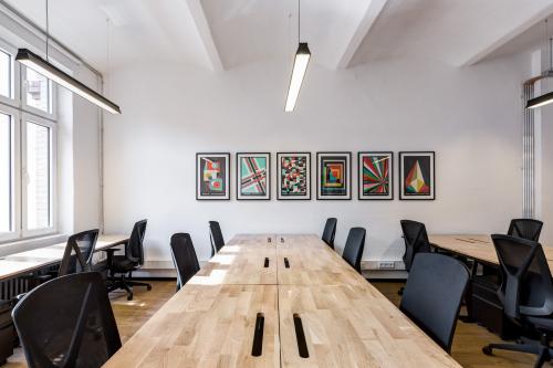 Modernes Büro in der Skalitzer Straße 104, Berlin Kreuzberg mit Holztischen und schwarzen Bürostühlen, Kunstwerke an der Wand.