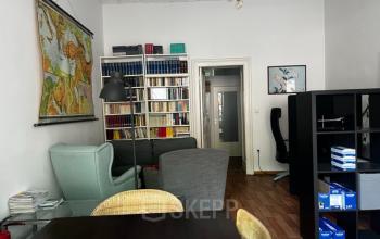 Gemütlicher Büroraum mit Bücherregalen, Weltkarte und mehreren Sitzgelegenheiten in der Wrangelstraße 22, ideal für alle, die Bürofläche mieten möchten.