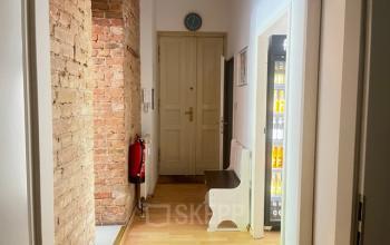 Blick auf einen schlichten, möblierten Flur mit Ziegelwand im Bürogebäude Wrangelstraße 22 in Berlin Kreuzberg. Ein Feuerlöscher und eine Bank sind sichtbar. Perfekt für Büroraum mieten geeignet.