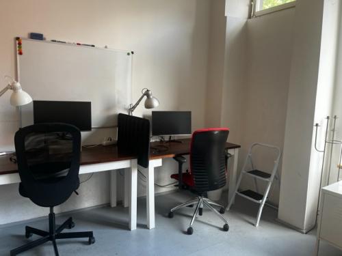 Bright office space at Wrangelstraße 22 in Berlin Kreuzberg, featuring two workstations, a whiteboard, and modern chairs. Ideal for productive workdays. Office space rental available.