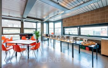 Heller Büroraum mit großen Fenstern in der Rudi-Dutschke-Straße 23, Berlin Kreuzberg, ideal zum Bürofläche mieten mit modernen orangen Stühlen und Tischgestaltung.