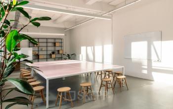 Helles Büro in der Mehringdamm 33, Berlin Kreuzberg, mit weißen Wänden und minimalistischem Design, mehreren Holzhockern und einer großen Tischfläche.
