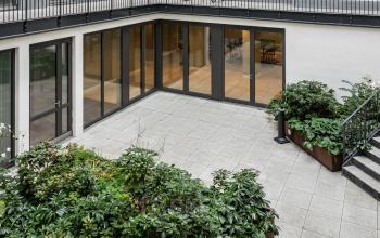Moderner Innenhof mit Pflanzenbeeten und großen Glasfenstern, die einen Blick in das Bürogebäude an der Chausseestraße 29 in Berlin Kreuzberg bieten.
