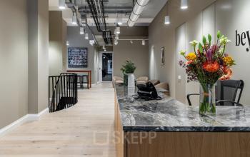 Modernes Büro in der Chausseestraße 29, Berlin Kreuzberg, mit stilvollem Empfangsbereich und Marmor-Theke. Perfekt für büroraum mieten. Große Blumenarrangements zieren den Raum.