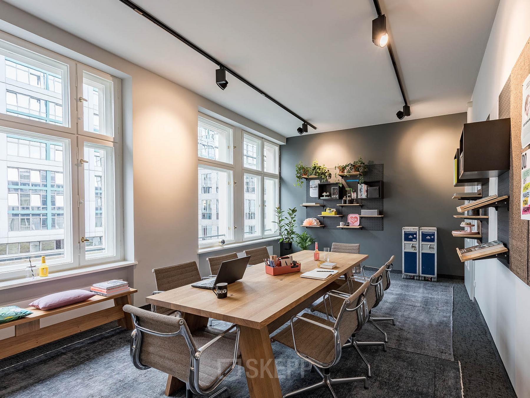 Helles Büro in Berlin Mitte, Unter den Linden 26-30, mit großem Schreibtisch und modernen Stühlen. Pflanzen und Regale ergänzen die freundliche Atmosphäre.