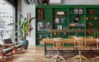 Ein stilvoller Büroraum in Berlin Mitte, Friedrichstraße 68, mit einem großen Holztisch und grünen Regalen. Perfekt zum Büroraum mieten.