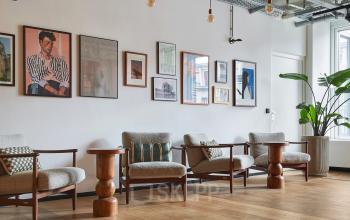 Lounge-Bereich im Büro Friedrichstraße 68, Berlin Mitte, mit stilvollen Sitzmöglichkeiten und dekorativer Wandkunst, ideal für Besprechungen und Networking, geeignet für Unternehmen, die Büroraum mieten möchten.