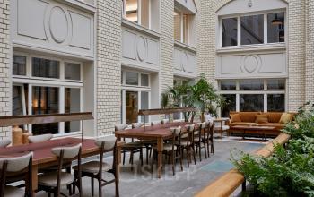 Innenansicht eines stilvollen Bürogebäudes in Berlin Mitte, Krausenstraße 9. Moderne Sitzgelegenheiten und Tische laden zur Zusammenarbeit ein, Ideal für Büroflächen mieten.