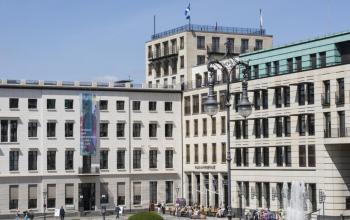Außenansicht des Bürogebäudes am Pariser Platz 6a, Berlin Mitte, mit mehreren Personen, die das Gebäude betreten oder verlassen.