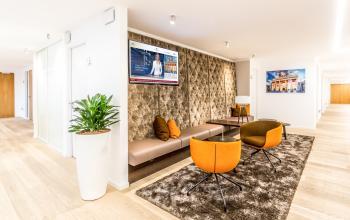 Gemütliche Lounge im Büro zur Miete am Pariser Platz 6a in Berlin Mitte mit modernen Sesseln und Wandbild.