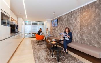 Büro in Pariser Platz 6a, Berlin Mitte mit gemütlichem Loungebereich, drei Menschen in geschäftlicher Besprechung und modernem Design. Ideal für Büroraum mieten.