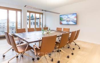 Moderner Konferenzraum im Bürogebäude Pariser Platz 6a, Berlin Mitte, mit großem Tisch, Ledersesseln und einem Bildschirm an der Wand. Ideal zum Büroraum mieten.