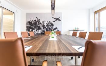 Moderner Konferenzraum zur Miete am Pariser Platz 6a, Berlin Mitte, geschmackvoll eingerichtet mit großem Holztisch und braunen Lederstühlen.
