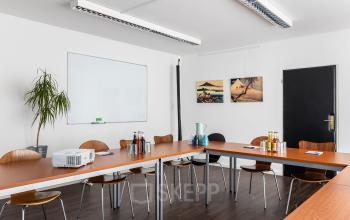 Modernes Büro in An der Kolonnade 11, Berlin Mitte, mit langer Holztisch-Formation, Stühlen und Präsentationstechnik, ideal zum Büroraum mieten für Meetings.