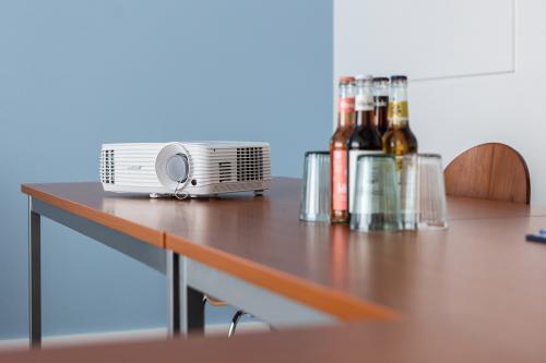 Konferenzraum in An der Kolonnade 11, Berlin Mitte, mit Holztisch, Projektor und Getränken. Bürofläche mieten.