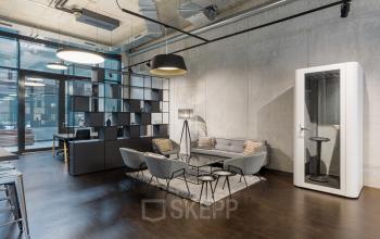 Modern office space at Hussitenstraße 32 in Berlin Mitte with stylish furnishings, including a sofa, chairs, and a phone booth, available for office space rental.