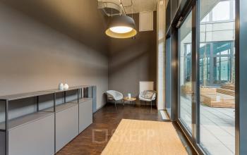 Modern office space available for rent at Hussitenstraße 32, Berlin Mitte, featuring minimalist decor, cozy seating, and large windows opening to a terrace.