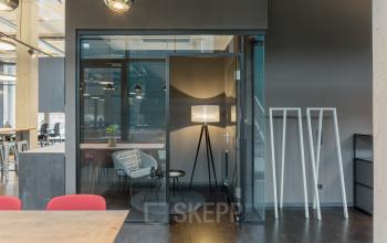 Modern office space rental at Hussitenstraße 32, Berlin Mitte, featuring stylish workspaces with glass walls, a cozy seating area, and chic decor.