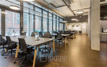 Spacious office with modern furnishings located at Hussitenstraße 32, Berlin Mitte, showcasing open floorplan seating and large windows, ideal for office space rental.