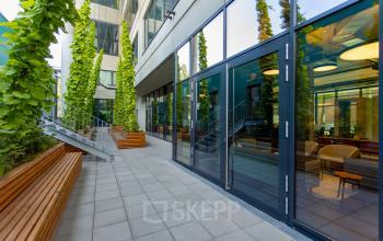 Modern exterior of office building at Hussitenstraße 32, Berlin Mitte with glass doors and vertical garden features.