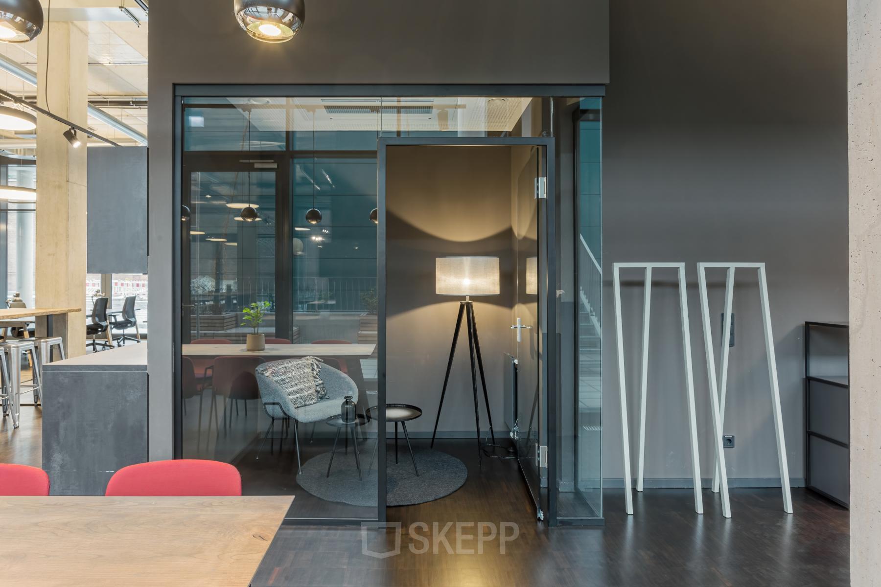 Modern office space rental at Hussitenstraße 32, Berlin Mitte, featuring stylish workspaces with glass walls, a cozy seating area, and chic decor.