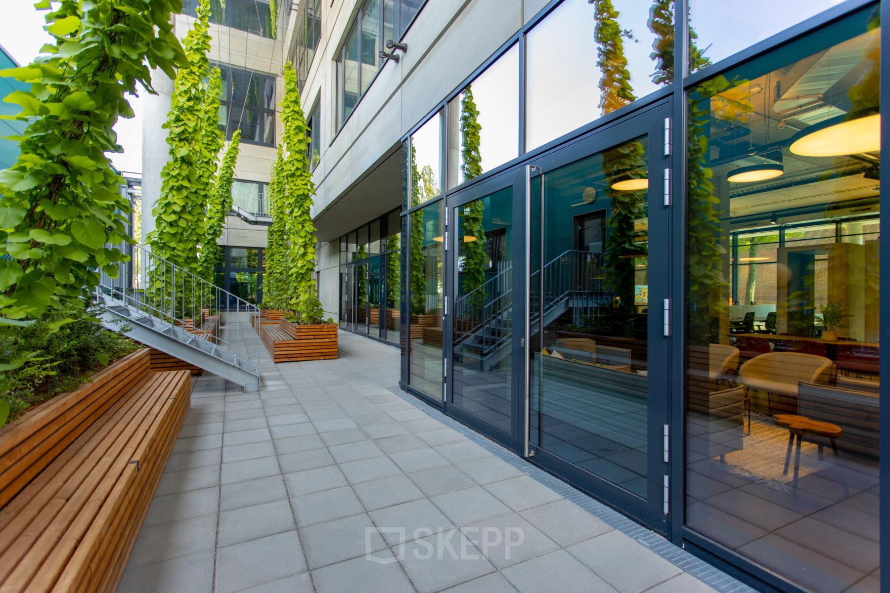 Modern exterior of office building at Hussitenstraße 32, Berlin Mitte with glass doors and vertical garden features.