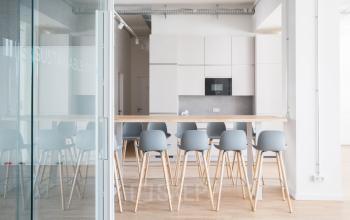 Küche und Essbereich eines modernen Büros in Neue Grünstraße 17, Berlin Mitte, mit hohen weißen Stühlen und Holztisch.