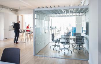 Modernes Büro in Neue Grünstraße 17, Berlin Mitte, mit großen Fenstern, Besprechungsraum und offener Arbeitsfläche. Mitarbeiter in Geschäftsgesprächen. Büro mieten in zentraler Lage.