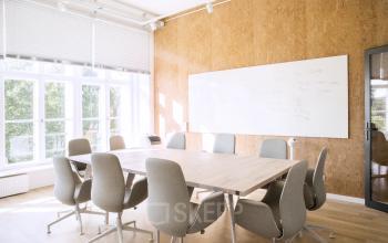 Heller Konferenzraum im Büro Neue Grünstraße 17, Berlin Mitte mit einem langen Tisch, umgeben von grauen Stühlen, ideal zum Büroraum mieten.