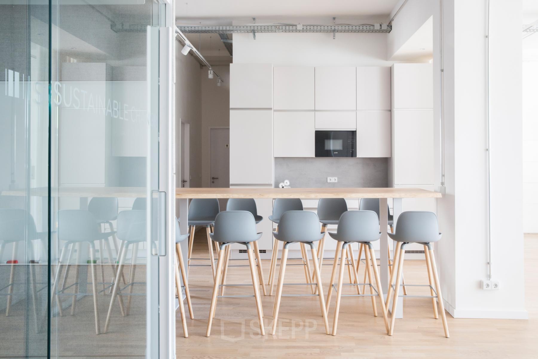 Bright, modern office furniture with high stools around a communal table in Neue Grünstraße 17, Berlin Mitte, available for office space rental.