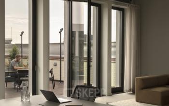 Modernes Büro in Unter den Linden 40, Berlin Mitte, mit Terrasse und Fenstern. Eine Person arbeitet am Laptop.