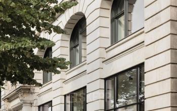 Außenansicht des Bürogebäudes Unter den Linden 40 in Berlin Mitte. Ein Mensch betritt das Gebäude durch eine Glastür.