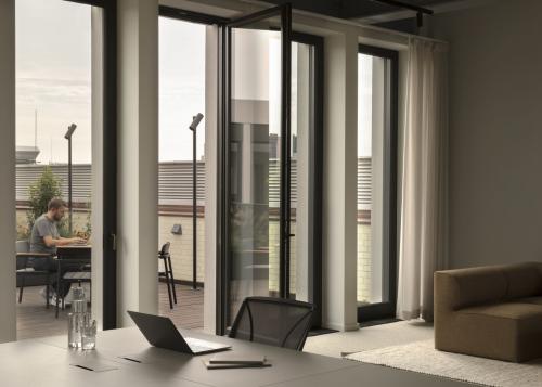 Modernes Büro in Unter den Linden 40, Berlin Mitte, mit Terrasse und Fenstern. Eine Person arbeitet am Laptop.