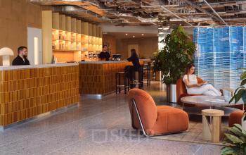 Modernes Büro in der Karl-Liebknecht-Straße 29a, Berlin Mitte: Empfangsbereich mit stilvollen Möbeln und Personen bei geschäftlichen Aktivitäten.