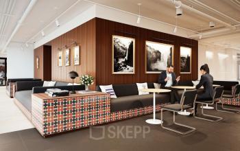 Modernes Büro mit Sitzgelegenheiten und Kunstwerken an der Wand in der Rosenthaler Straße 43-45, Berlin Mitte. Zwei Personen diskutieren Geschäftliches an einem Tisch.