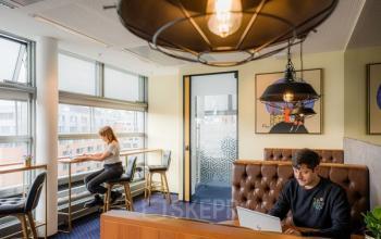 Moderne Bürofläche in Berlin Mitte, Linkstraße 2, mit zwei Personen bei der Arbeit an Schreibtischen in einem gut beleuchteten Raum.