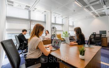 Moderner Büroraum zur Miete in der Linkstraße 2 in Berlin Mitte mit mehreren Personen, die an Schreibtischen arbeiten.