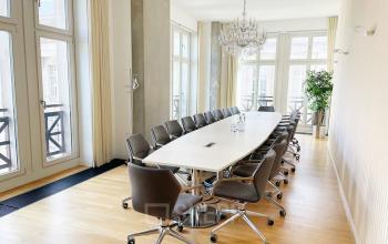 Moderner Konferenzraum im Büro Unter den Linden 10, Berlin Mitte, mit langem Tisch und stilvollen Bürostühlen unter einem Kronleuchter.