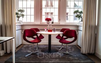 Moderner Besprechungsbereich mit runden Tisch und roten Stühlen, ideal um Büroraum im Berliner Bezirk Mitte zu mieten.