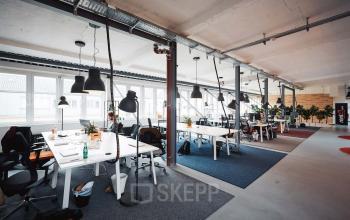 Moderner Coworking-Bereich in großem Büroraum mit viel Lichteinfall