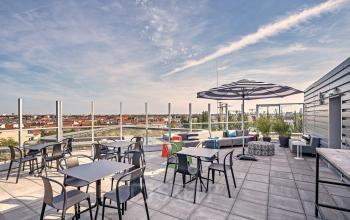 Dachterrasse am EUREF-Campus 22 in Berlin Schöneberg mit Sitzgelegenheiten, Tischen und Sonnenschirmen. Perfekter Ort für Pausen im Freien.