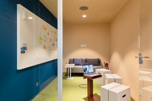 Moderner Büroraum am EUREF-Campus 22 in Berlin Schöneberg mit einem Whiteboard, einem kleinen Tisch und einer Couch. Ideal für kreatives Arbeiten und Meetings. Perfekt zum Büro mieten.
