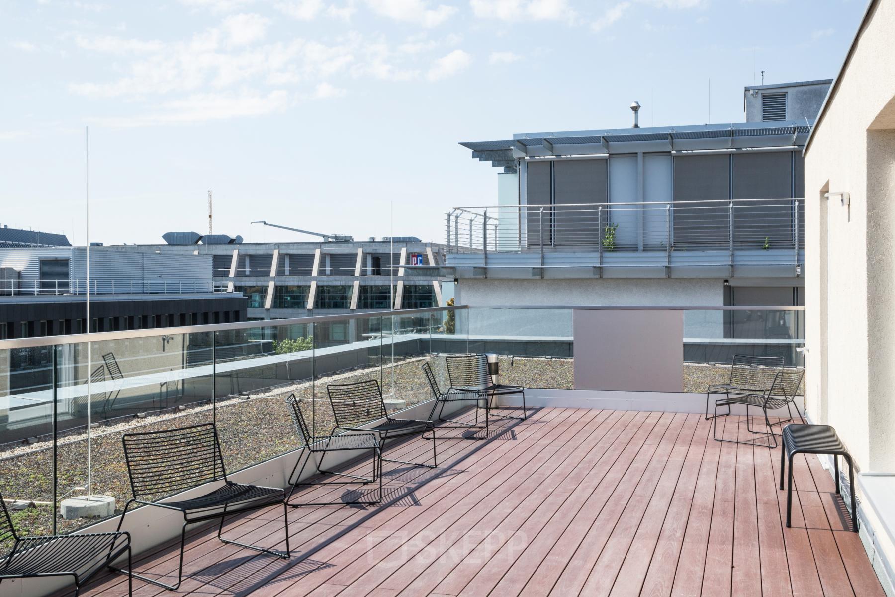 Spacious outdoor terrace at office space rental located at Nürnberger Straße 8, Berlin Tiergarten, featuring modern seating and views of surrounding buildings.