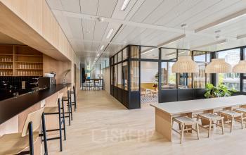 Moderner Büroraum in Bern, Weltpoststrasse 5, mit hellen Holztönen und stilvollen Möbeln. Ideal, um Bürofläche zu mieten. Elegantes Design mit Sitzmöglichkeiten und flexiblen Arbeitsbereichen.