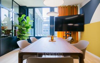 Moderner Büroraum in Bern, Weltpoststrasse 5, mit großem Tisch, Pflanzen und großem Bildschirm; ideal zum Bürofläche mieten.