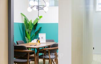 Moderner Büroraum mit stilvollem Mobiliar in Bern, perfekt zum Büro mieten. Ein heller Besprechungstisch mit eleganten Stühlen und Pflanzen sorgt für eine angenehme Atmosphäre.