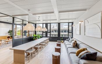 Moderner Büroraum mit großem Tisch und gemütlichen Sofas in Bern, ideal zum Bürofläche mieten.