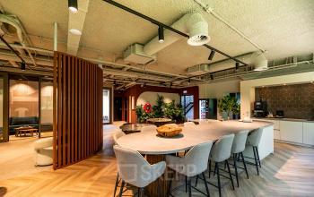 Spacious office interior at De Maas 8, Best, featuring modern furnishings with a large communal table and seating, ideal for flexible office space rental.